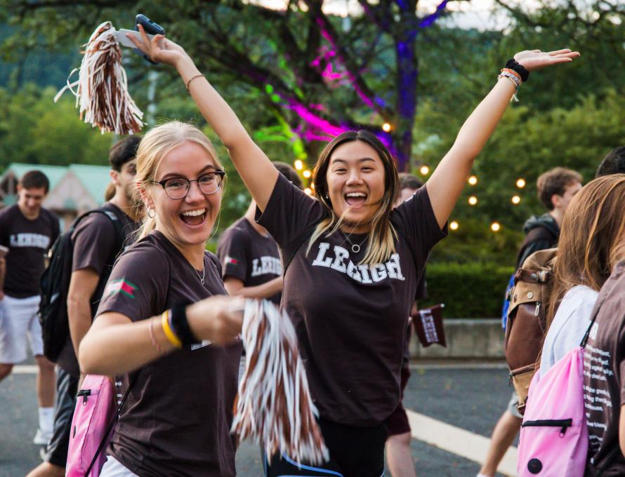 Two female students wearing brown Lehigh t-shirts while celebrating at the Rally 