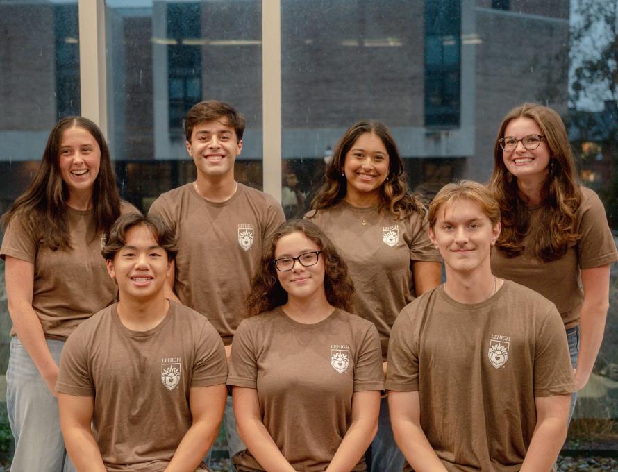 Seven students wear matching brown Lehigh shirts with a white school crest and smile.