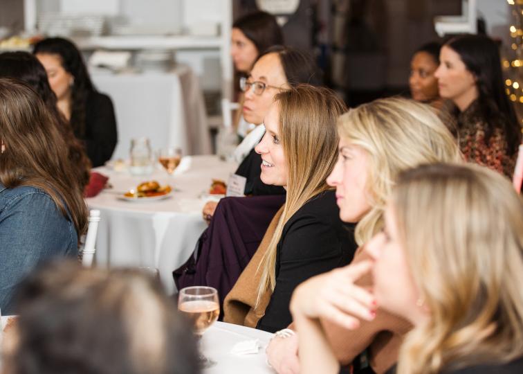 Women sitting around rounds tables with white table cloths