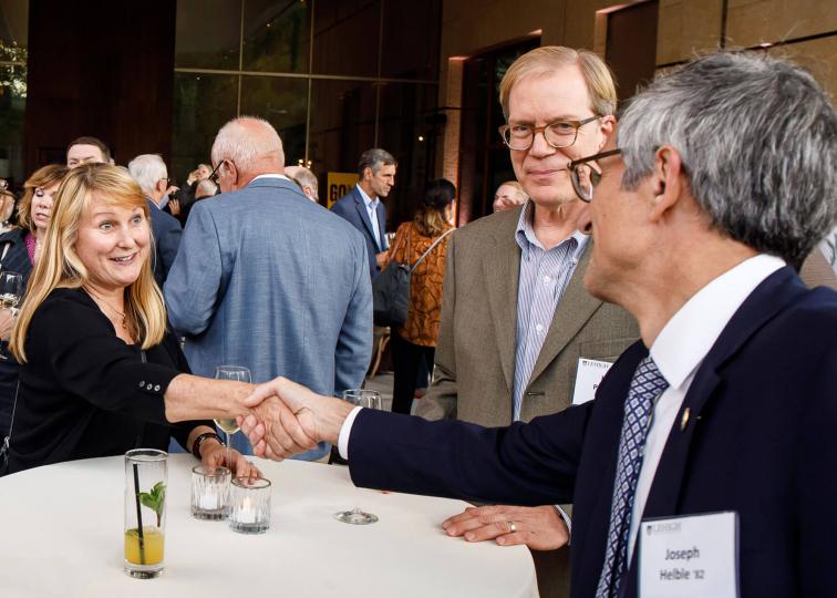 President Joseph J. Helble shaking a woman's hand over a white tablecloth