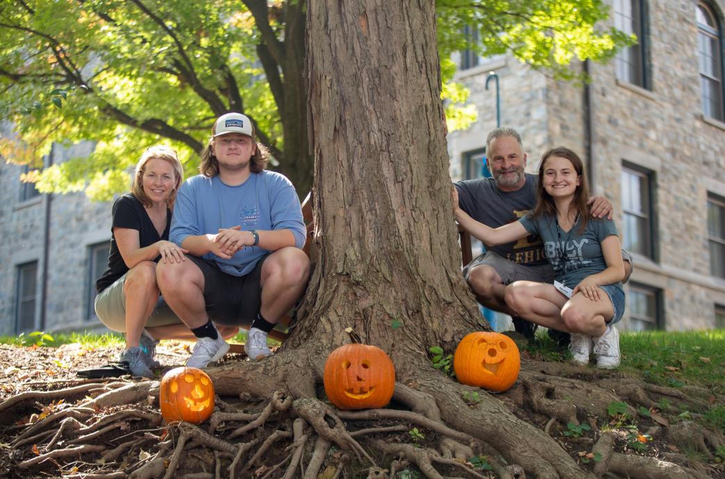 Pumpkin carvers gathered around their finished pumpkins