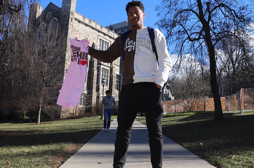 Student jumps in the air while holding a shirt
