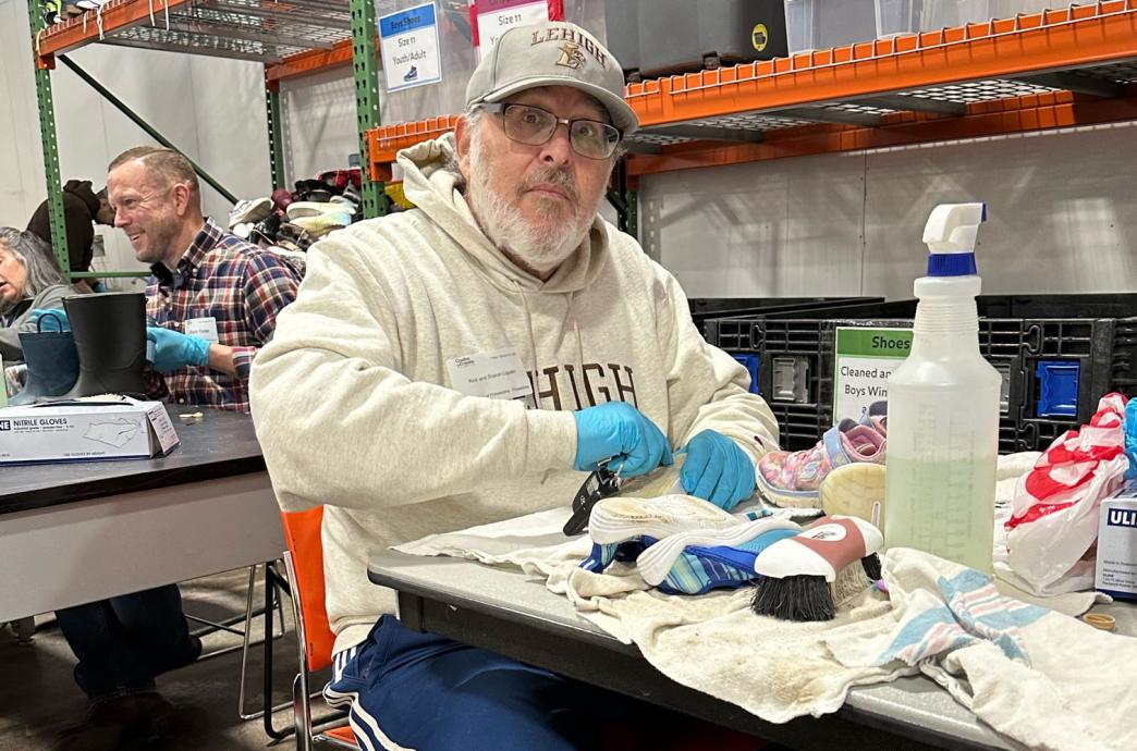 A man in Lehigh gear cleaning the sole of a sneaker