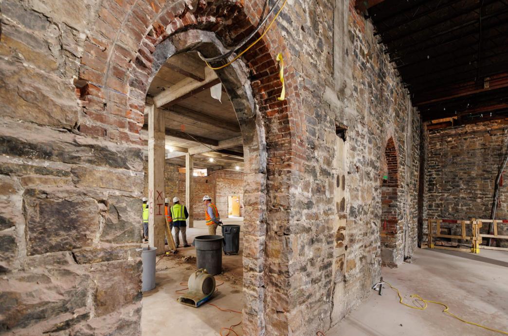 Construction workers and others seen through brick and stone arched doorways