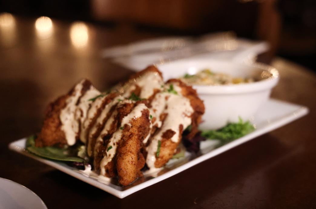 A plate of crispy buttermilk fried chicken dressed in creamy sauce 