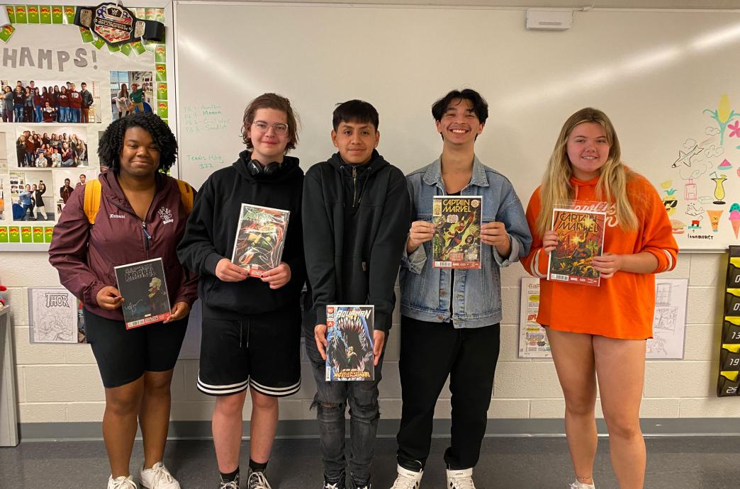 Fans standing in a classroom holding signed copies of "Captain Marvel" by Kelly Sue Deconnick