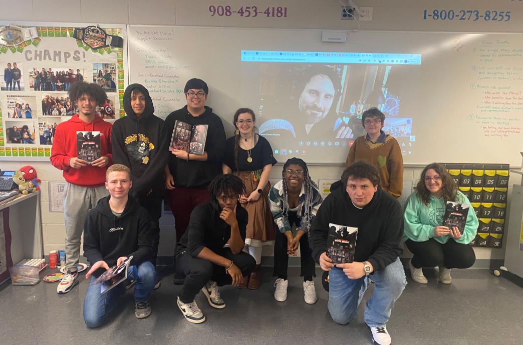 Sean Gordon Murphy smiles as fans pose with a projected image of him during a virtual meet and greet