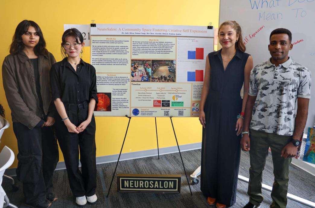 Areesha Ahmed, Mo Chen, Emma Camp, and Zelalem Ayalew stand next to a poster about their project