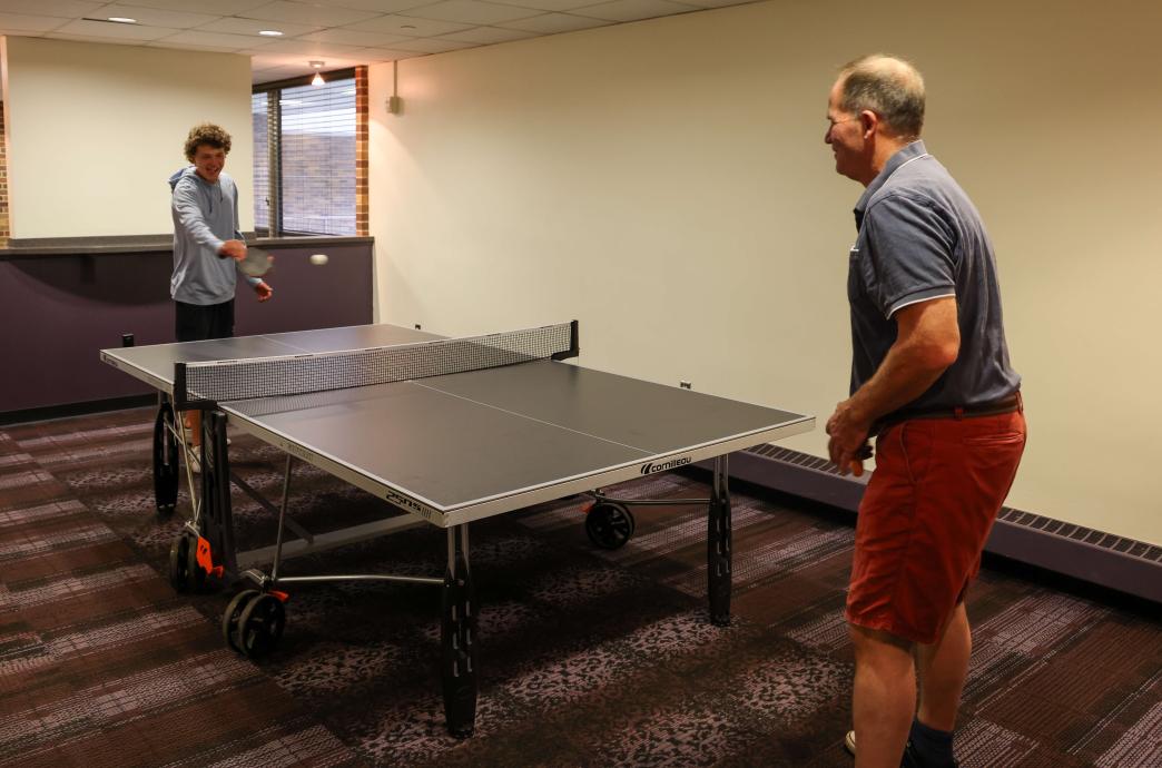 A student and his dad playing ping pong