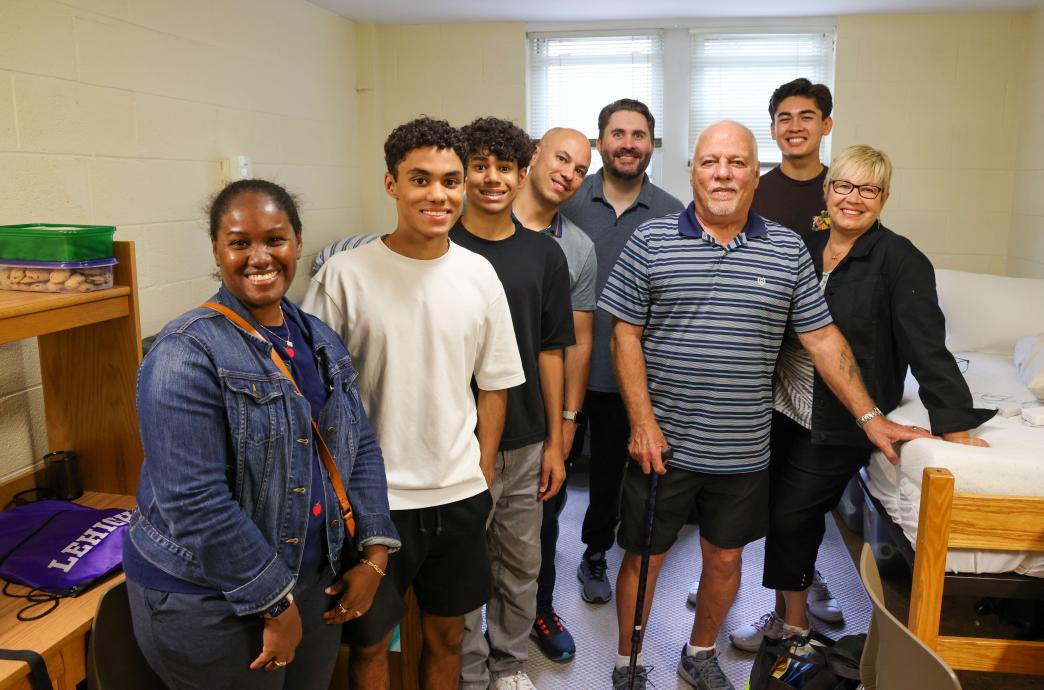 A large family poses for a photo in a dorm room