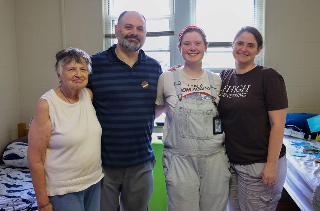 A family poses for a photo in a dorm room