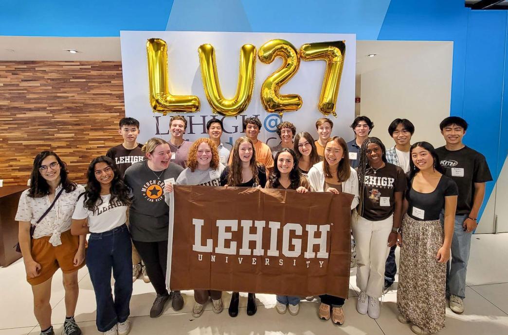 Incoming students holding a brown Lehigh University flag in the Lehigh Nasdaq Center