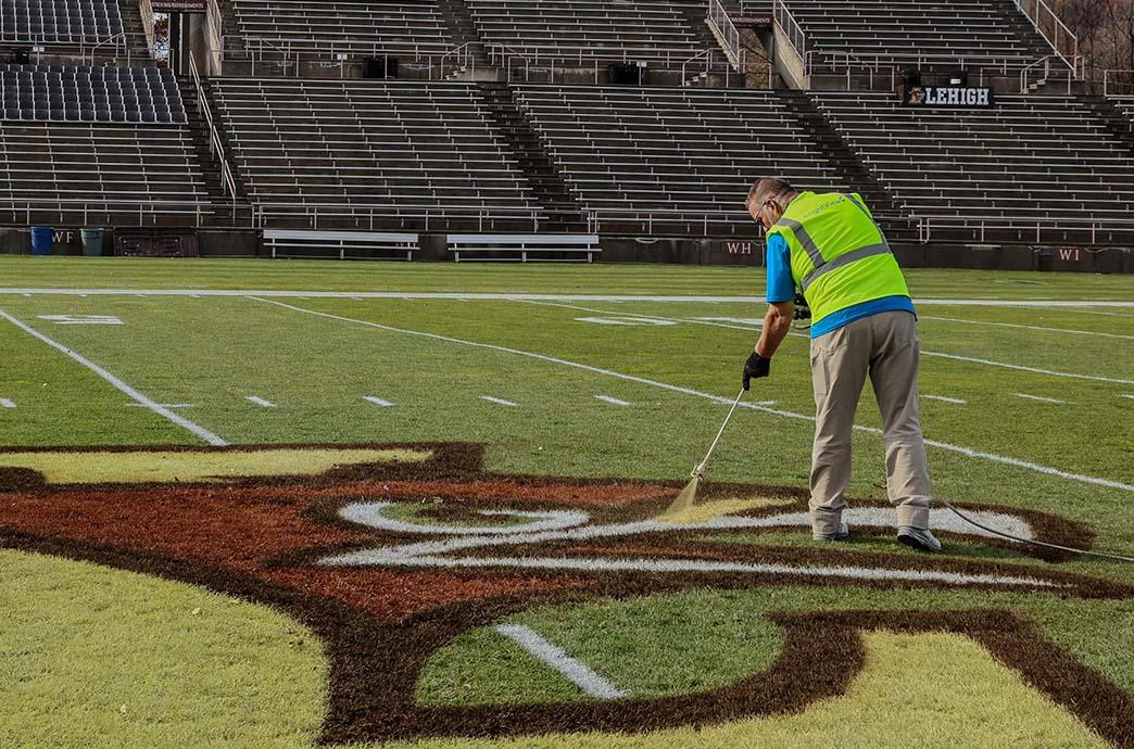 Eric Steckel painting the Lehigh University Athletics logo at midfield of Goodman Stadium.