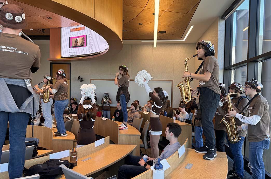 Students watch Lehigh University's marching band performances on the desks of a classroom in the Business Innovation Building.