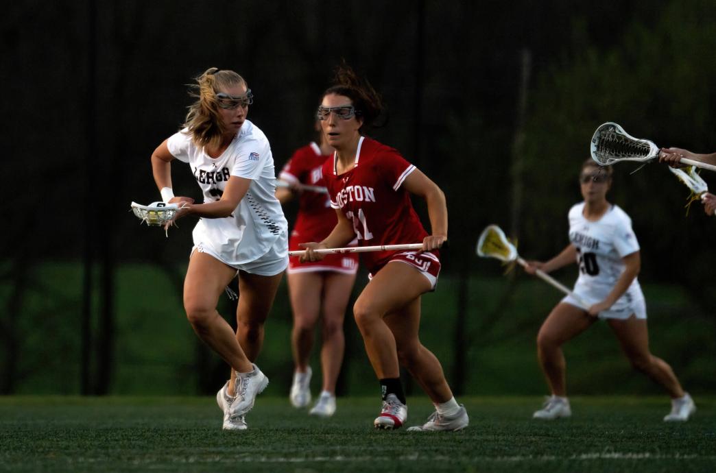 Lehigh women's lacrosse player running ahead of a player from Boston