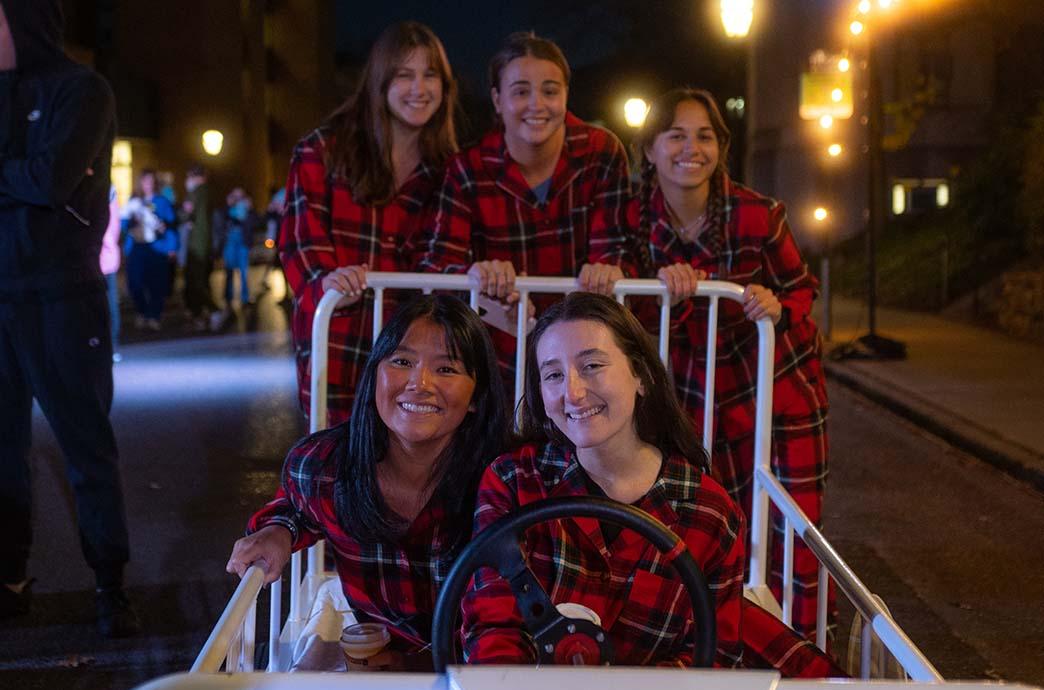 Five students in matching pajamas posed for a photos in their bed-shaped racing car while on Packer Avenue at night.