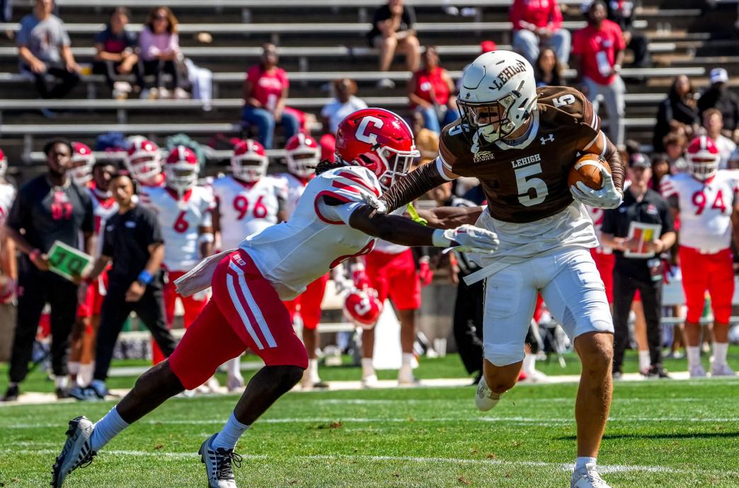 Lehigh football player running and blocking the ball past a player from Cornell