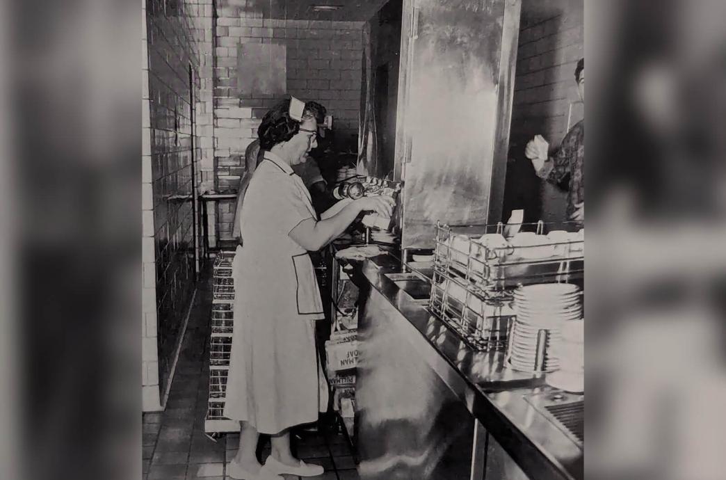 Black and white photo from the 1963 yearbook shows a woman using the milk machines in the University Center dining hall.