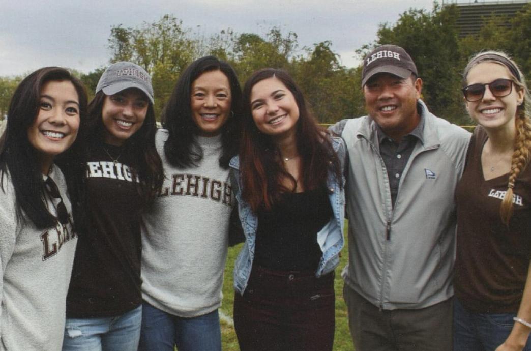 Alumni wearing Lehigh attire stand shoulder-to-shoulder and pose smiling for the camera