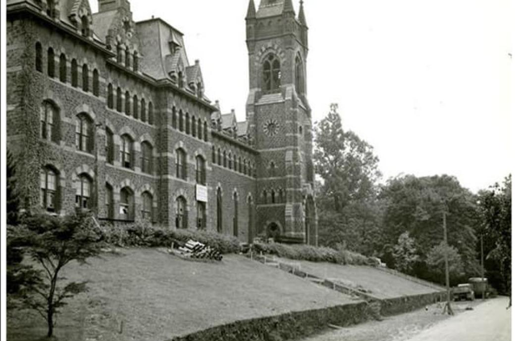 A black and white photo from 1955 of the UC shows a sign on the building and the lawn covered with construction equipment.
