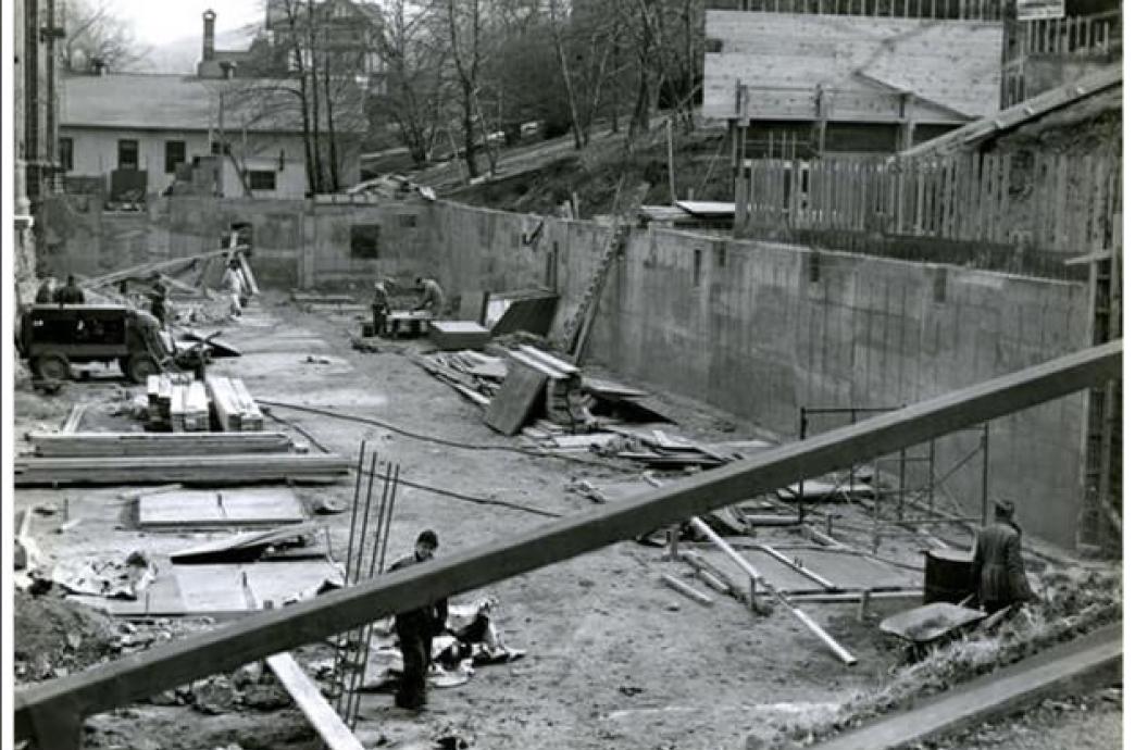A 1955 black and white photo of the exposed foundation of the UC, filled with construction workers, vehicles, and equipment.