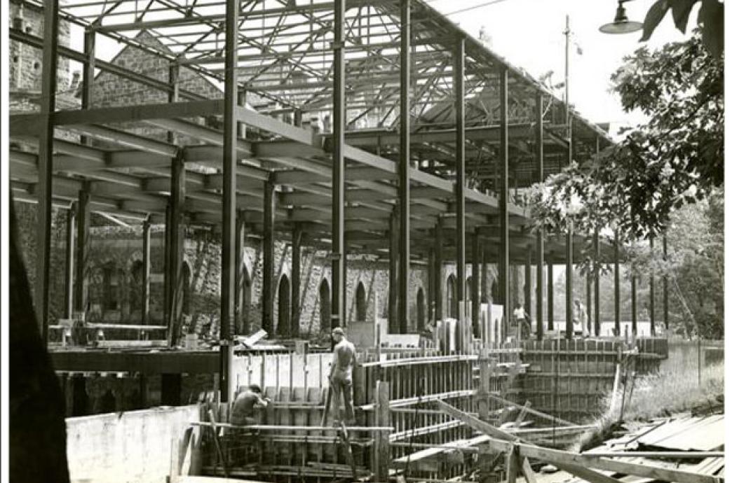 A 1955 black and white photo of the UC construction shows men at work on the new addition with scaffolding and support beams.