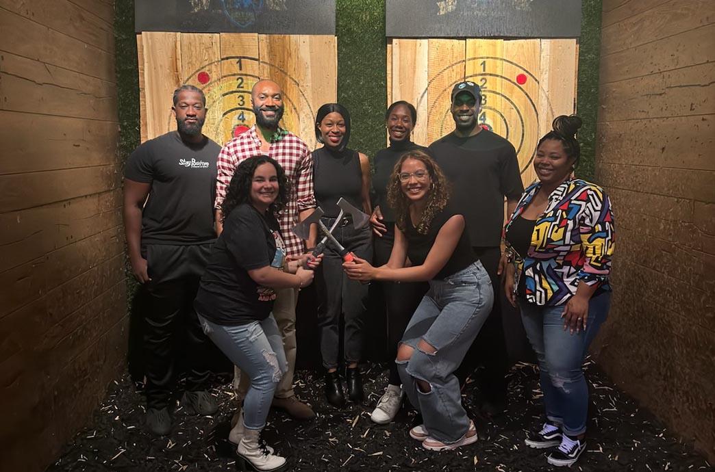 BALANCE members pose with axes at its axe throwing event.