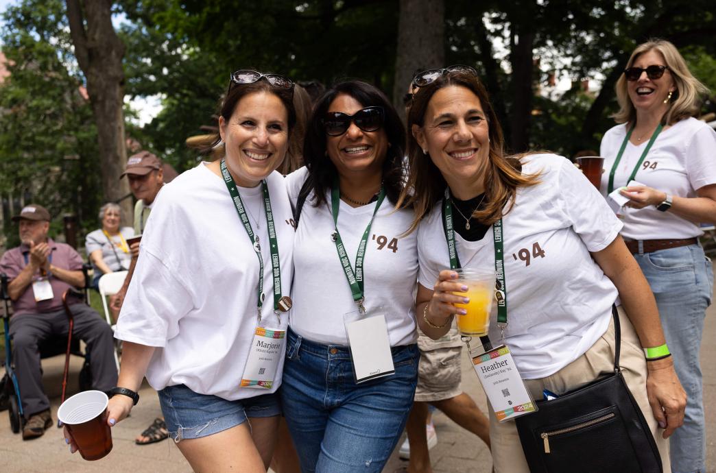 Three women pose for a photo wearing sunglasses, lanyards, and white '94 tshirts.