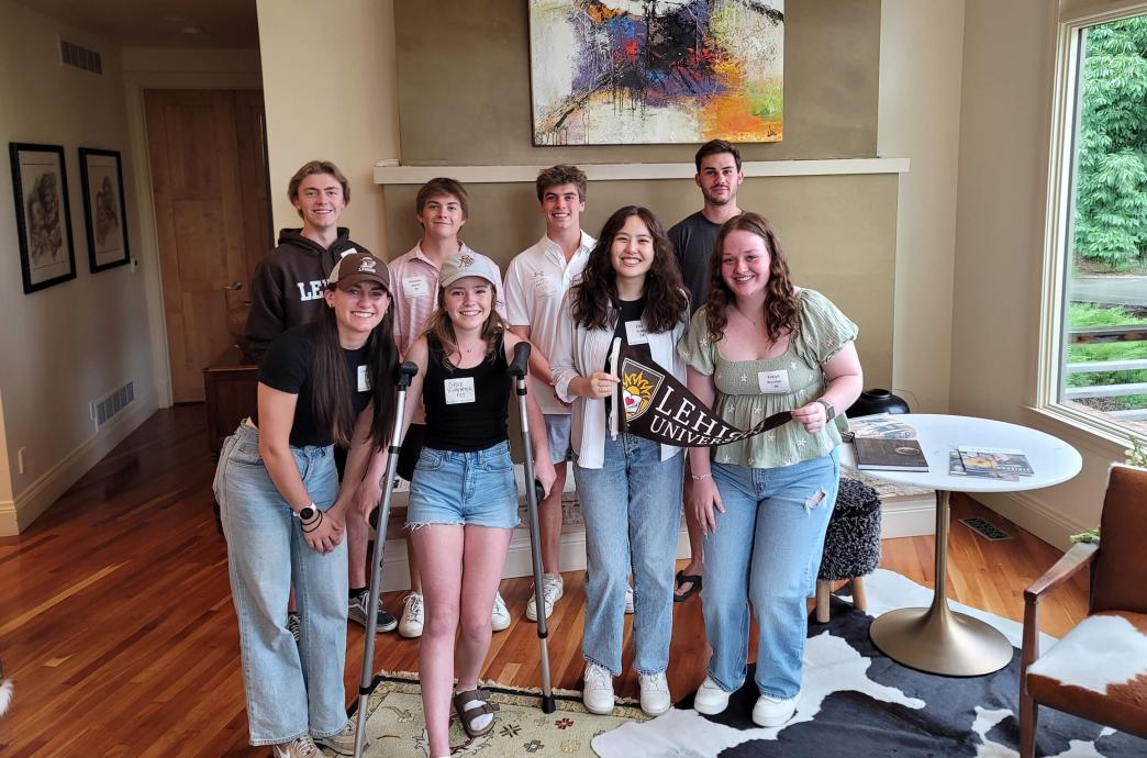 Students standing in the home of an alumni while smiling together.