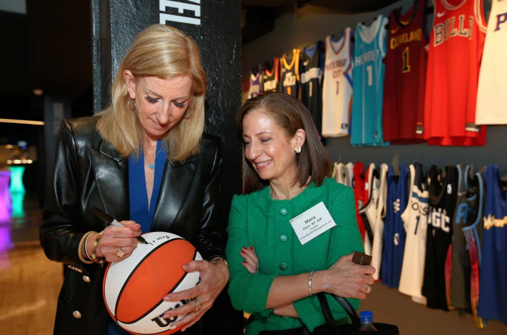 Cathy Englebert signing a basketball for another woman