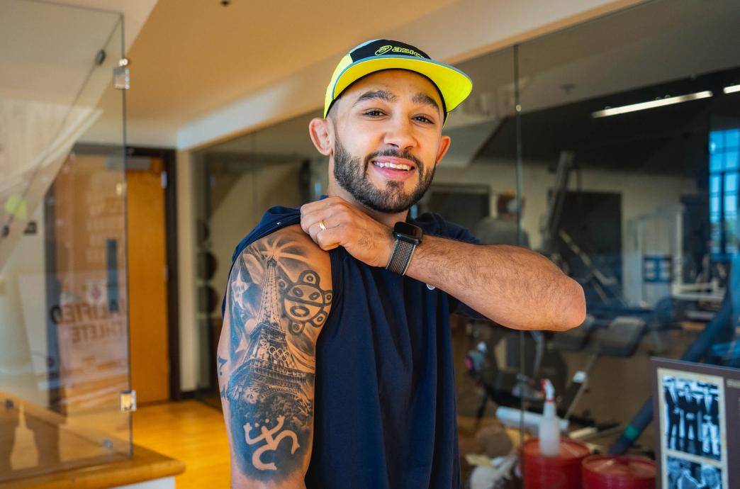 Darian Cruz holds his sleeve up to show a black and white tattoo, commemorating his Olympic run in Paris.