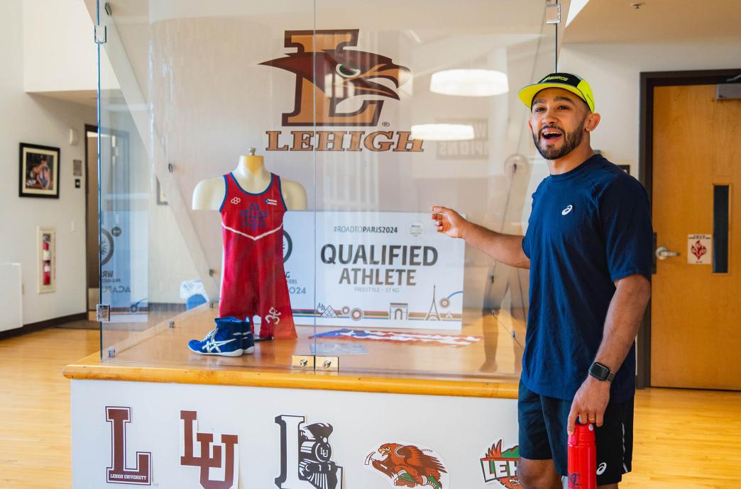 Darian Cruz points to a display showing his attire worn during the Olympic trials for Paris 2024.