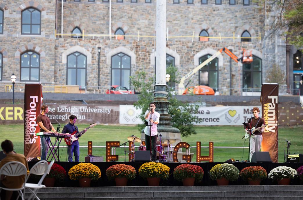 A band performs on a stage with marquee Lehigh letters and the University Center construction serving as a backdrop.