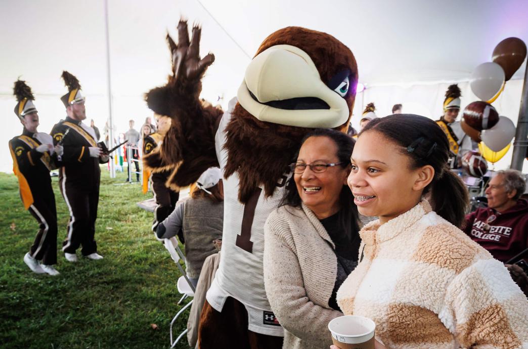 Lehigh Mountain Hawk mascot, Clutch, poses with attendees raising one arm raised in a wave.