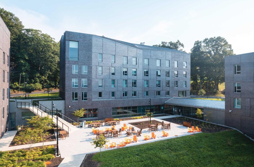 Three residence buildings surrounding an open courtyard filled with bright orange chairs.