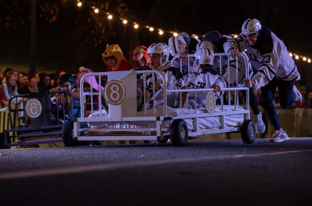 A bed races team wearing hockey gear races down Packer Avenue.