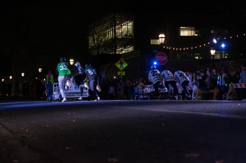Two bed races teams push their beds while racing down the street.
