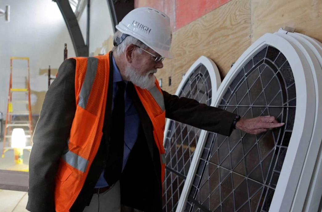 Beall Fowler stands in the former Asa Packer Ballroom and admires the refurbished stained glass windows, touching one.