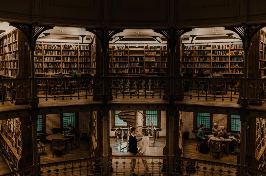 A wide angle across the room of Linderman library shows the top two floors with a man and woman facing each other on the second.