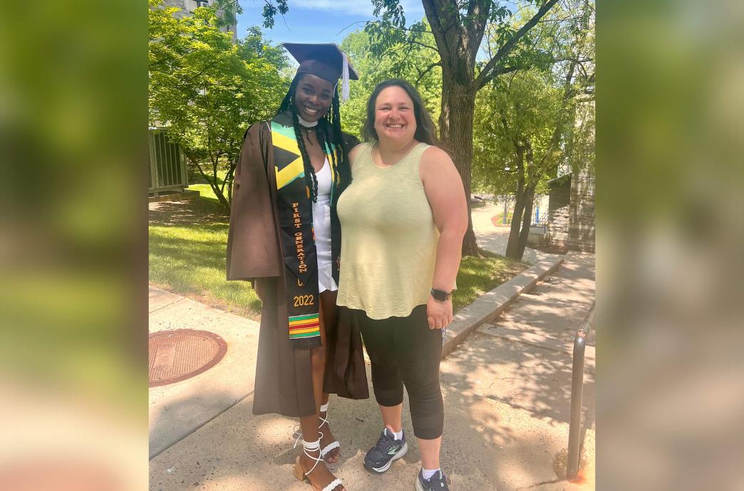 Carolina Hernandez poses beside a female student wearing a brown graduation cap and gown.