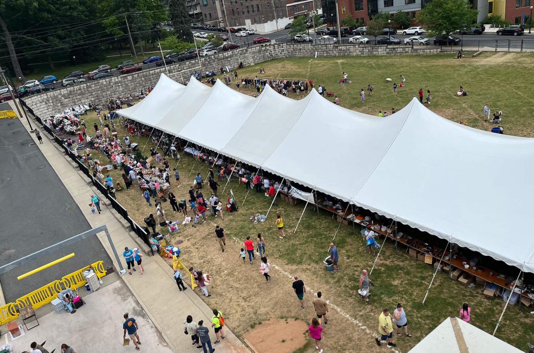 An aerial view of a large, long white tent with people and tables beneath it for the The Great South Side Sale.