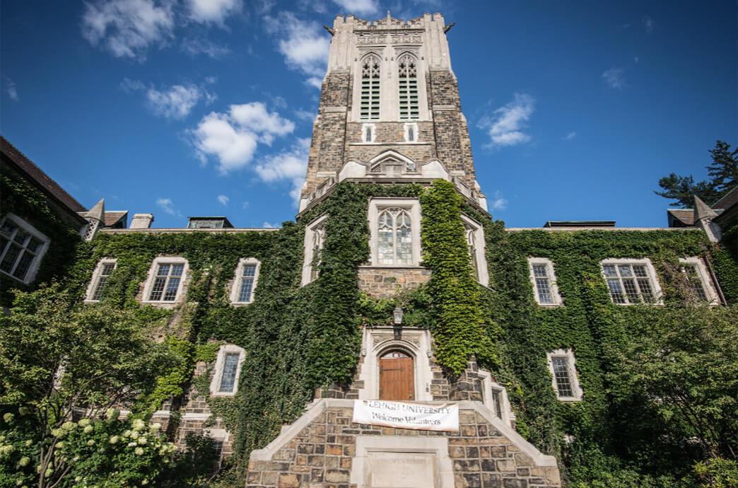 Alumni Memorial, a historic stone building with a tower covered in ivy on a bright summer day