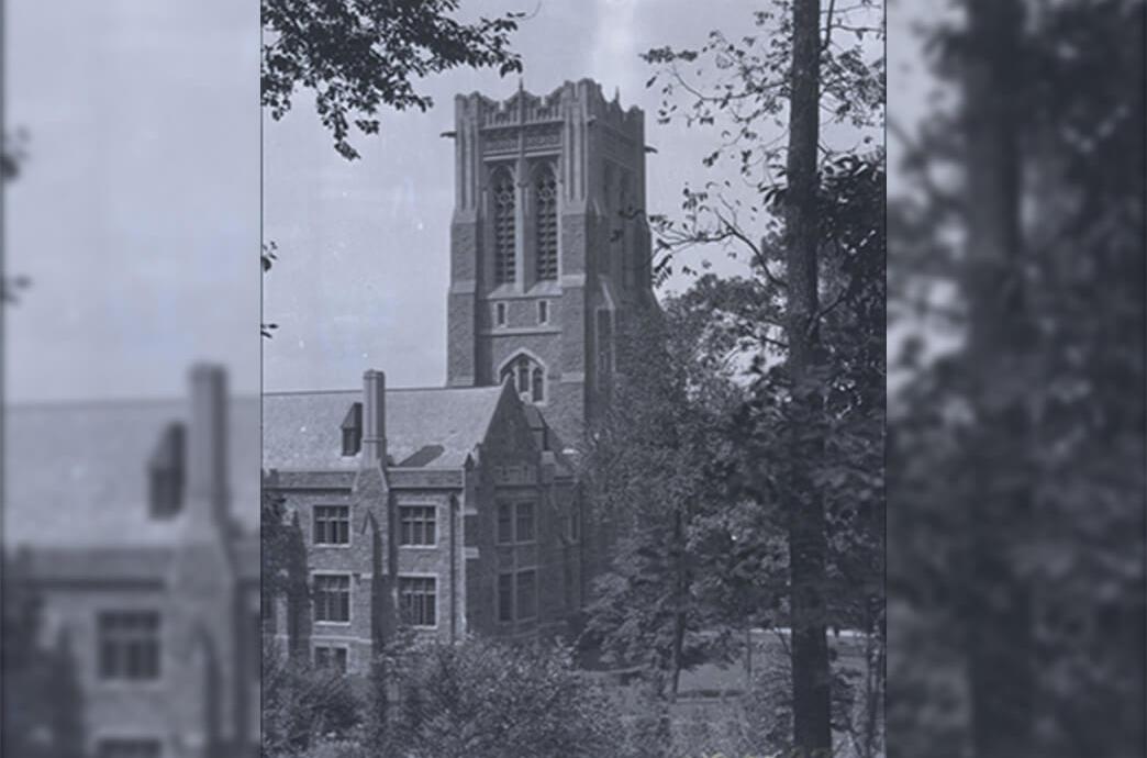 An older photo of a stone building surrounded by trees, showcasing historical architecture and natural scenery.