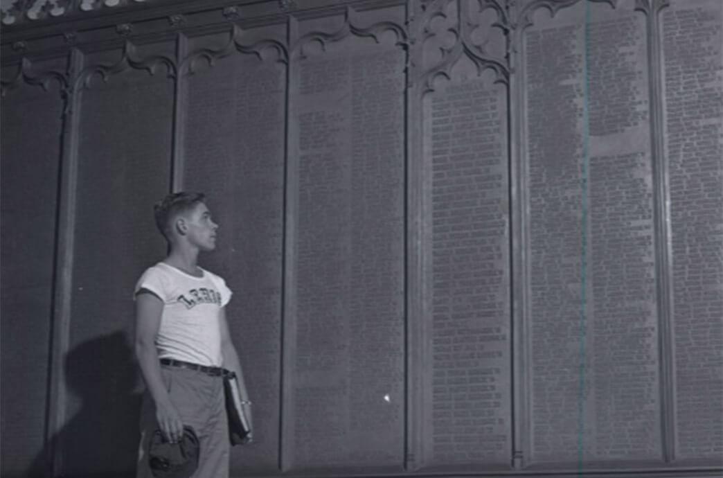A student stands before a wall covered with numerous names honoring Lehigh alumni who participated in WWI.