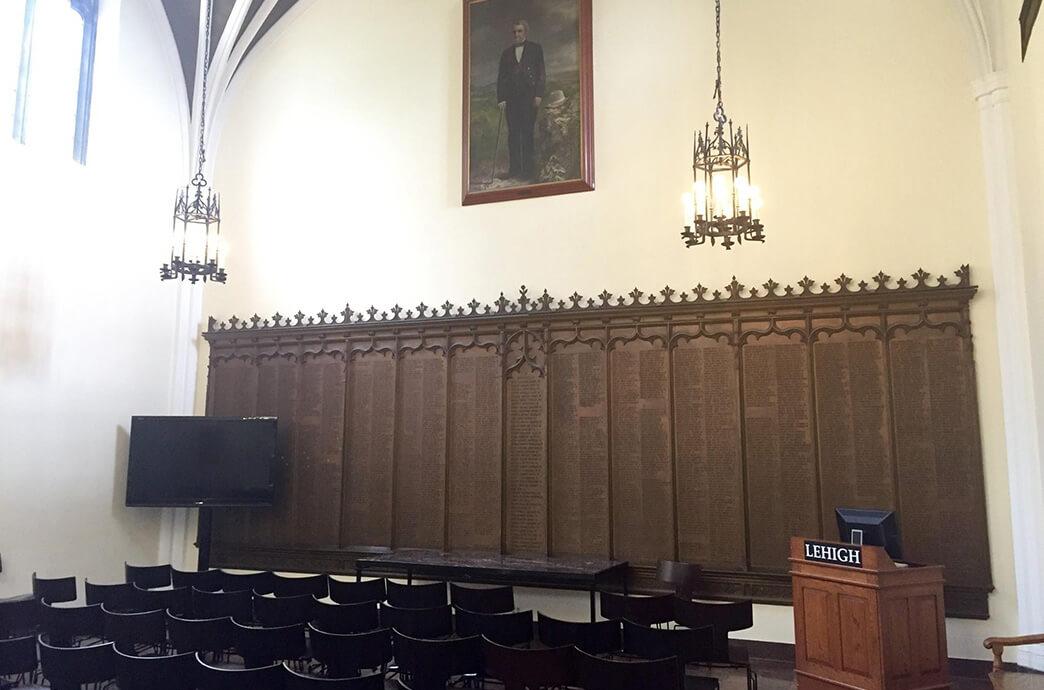 A spacious room featuring several chairs and a large wooden panel on one wall dedicated to Lehigh alumni who participated in WWI.