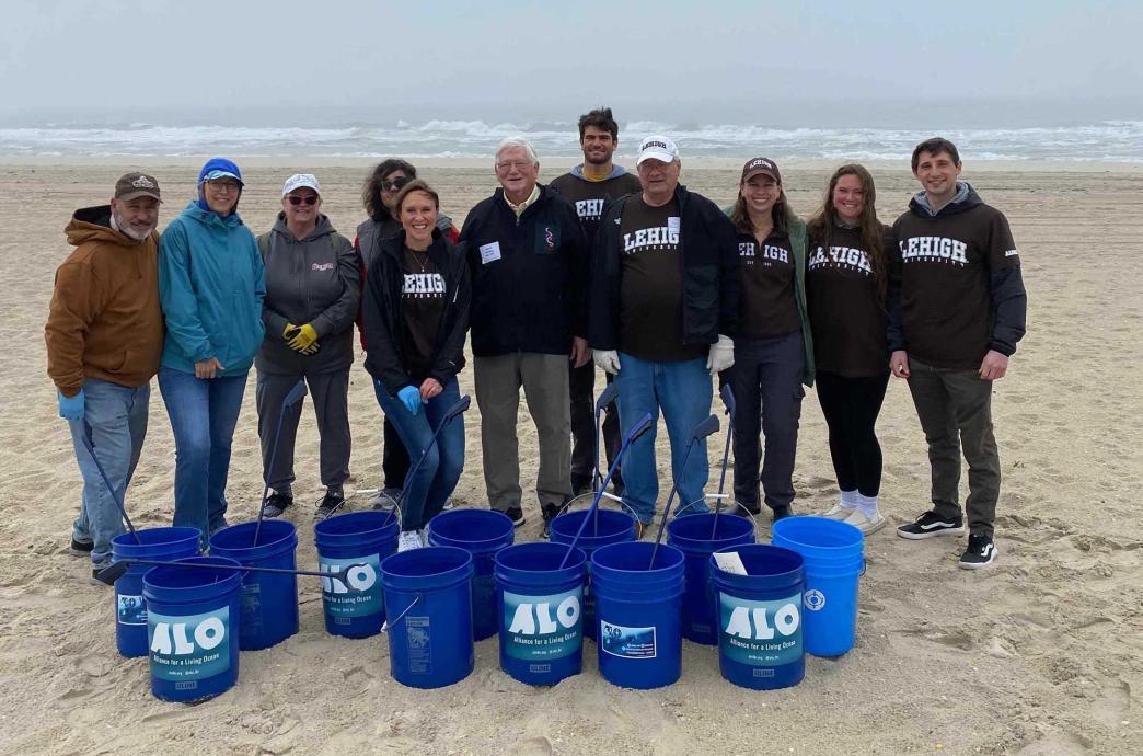 A group of alumni standing together on a sandy beach.