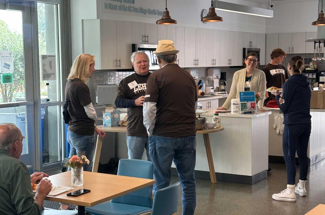 Alumni stand interspersed with residents throughout a kitchen.