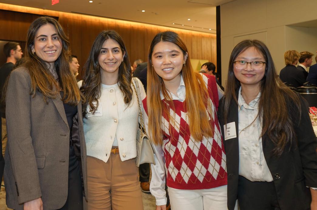 Four women stand and huddle for a photo with arms around each others shoulders, smiling.