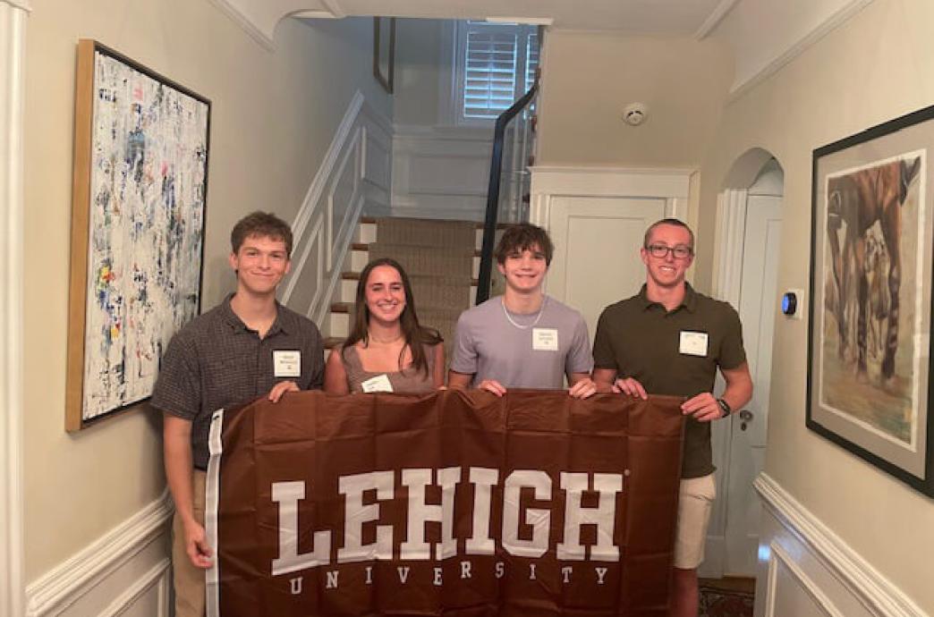 Group of four people holding a Lehigh banner indoors.