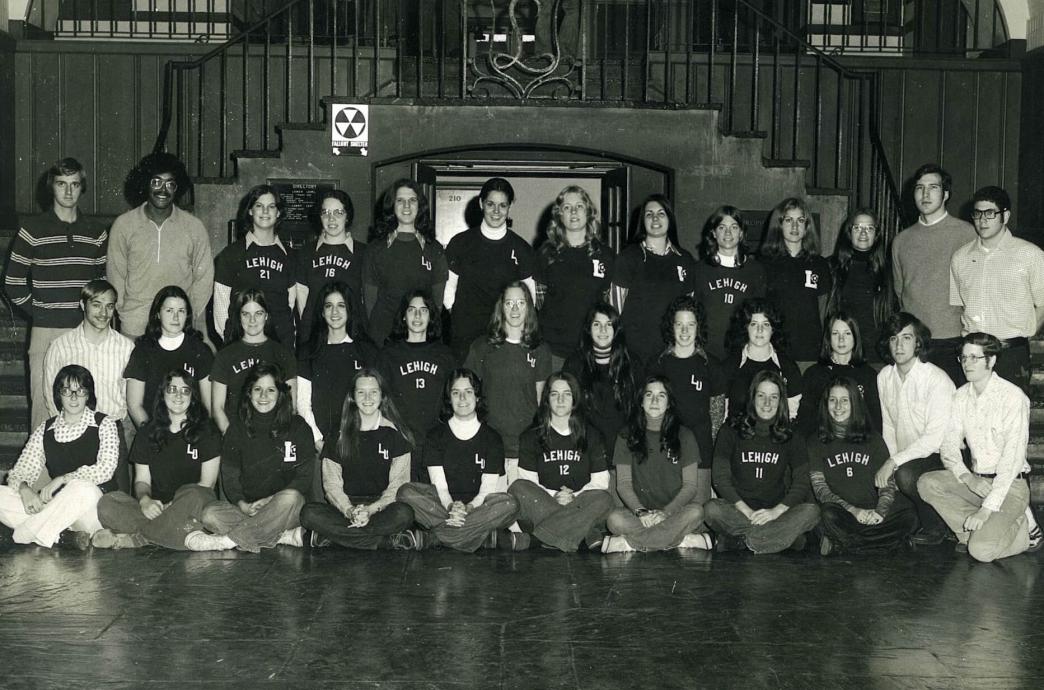 In a gymnasium, a group of women pose for a team photo in their uniforms.